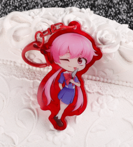 This is a bright red acrylic keychain with a red clasp. The character inside has pink hair bought back into two pig-tails. She's wearing a blue school uniform and is holding a knife in her hands.